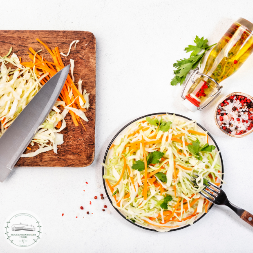 Ingredients for healthy coleslaw recipe, including shredded cabbage, carrots, and seasoning, displayed with a knife and cutting board.